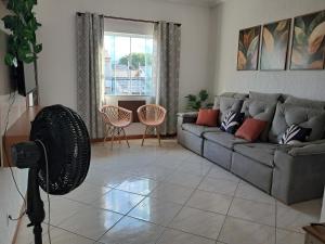 a living room with a couch and a fan at Refúgio do Abricó - apto com ar e garagem in Rio das Ostras