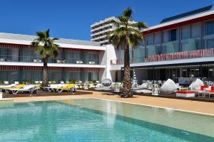 Pestana Alvor South Beach Premium Suite Hotel في ألفور: حمام سباحة أمام مبنى به أشجار نخيل