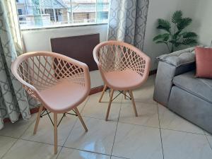 two pink chairs in a living room with a couch at Refúgio do Abricó - apto com ar e garagem in Rio das Ostras +26 photos
