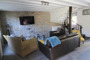 ein Wohnzimmer mit Sofas und einem TV an einer Backsteinwand in der Unterkunft Maison 8 personnes localisée au cœur de Sainte-Marie-du-Mont in Sainte-Marie-du-Mont
