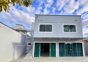 a white house with green doors and a sky at Vaz Beach Residence in Penha