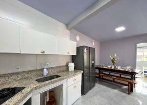 a kitchen with white cabinets and a black refrigerator at Vaz Beach Residence in Penha