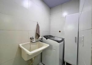 a white bathroom with a sink and a washing machine at Vaz Beach Residence in Penha +21 photos