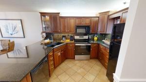 a kitchen with wooden cabinets and black appliances at Destin on the Gulf 701 in Destin +32 photos