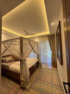 a bedroom with a bed with a canopy at beachfront hideaway 1bed with pool&ac in Diani Beach +3 photos