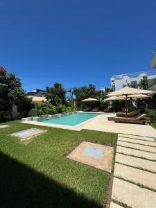 a swimming pool with an umbrella and some grass at beachfront hideaway 1bed with pool&ac in Diani Beach