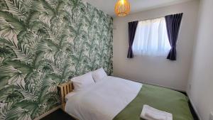 a bedroom with a bed with a tropical wallpaper at Klasse Villa Miyako in Miyako-jima