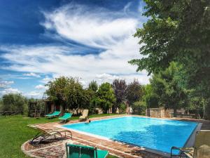una piscina in un cortile con sedie e alberi di Apartment in a farmhouse with swimming pool a Mensanello