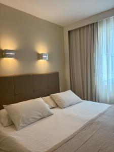 a large bed with white pillows and a window at Linhares Design Hotel LS in Linhares