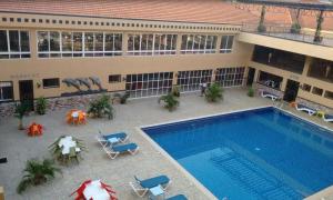 a swimming pool with chairs and umbrellas in front of a building at Imperial Golf View Hotel in Entebbe