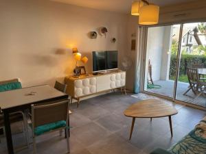 ein Wohnzimmer mit Fernseher und Tisch in der Unterkunft Appartement de standing avec jardin privatif, proche du lac et du centre, parking inclus - FR-1-239-583 in Soorts-Hossegor