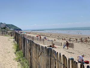 a group of people on a beach near a wooden fence at Appartement cosy à 200m de la mer, 2 chambres, centre-ville de St Pair-sur-Mer, parking inclus - FR-1-361-543 in Saint-Pair-sur-Mer