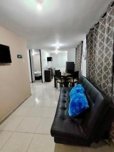 a living room with a black leather couch with a blue blanket at Apartamento a 2km del parque del Café, Full equipado in Montenegro