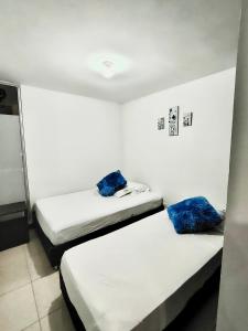 two beds in a white room with blue pillows at Apartamento a 2km del parque del Café, Full equipado in Montenegro +5 photos