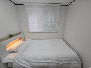 une petite chambre avec un lit blanc et une fenêtre dans l'établissement Day Rest House, à Séoul