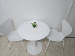 une table blanche avec trois chaises et une plante sur elle dans l'établissement Day Rest House, à Séoul