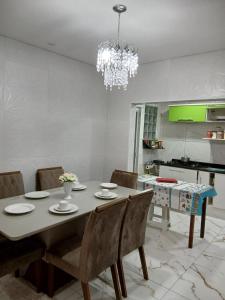a dining room table with chairs and a chandelier at Casa térrea com garagem! Região Central, próximo a Igreja in Aparecida