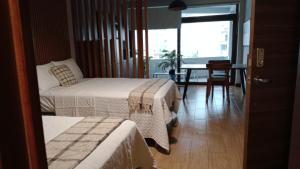 a hotel room with two beds and a table and a window at Oak 2B Loft Ejecutivo en zona 10 in La Aurora
