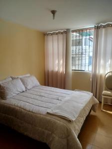 Un dormitorio con una cama y una ventana y una silla. en Beautiful cozy house, en Arequipa