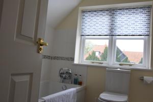 a bathroom with a window and a toilet and a tub at The Dolphin Inn in Thorpeness