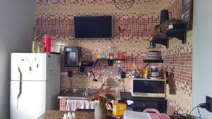 a kitchen with a brick wall with a microwave and a refrigerator at Yamara's somente mulheres in Manaus