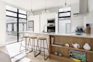 a kitchen with white cabinets and bar stools at Architectural Urban Diamond in Christchurch