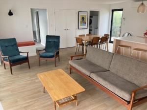 a living room with a couch and chairs and a table at Bubbles Bach-dog friendly, close to beach & shops! in Waihi Beach