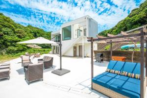 an outdoor patio with chairs and an umbrella at 熊野古道ビーチテラス串本 in Wabuka