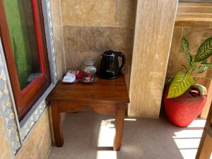 a table with a coffee maker on it next to a window at ERA Guest House in Ubud