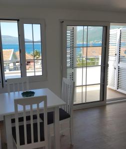 a dining room with a table and chairs and a view of the ocean at Apartment MilaS in Tivat