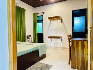 a bedroom with a bed and a table and a window at Aura Home Stay in Batticaloa