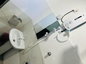a white bathroom with a sink and a mirror at Aura Home Stay in Batticaloa +14 photos