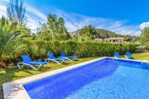 a swimming pool with blue lounge chairs next to a yard at Villa Voltor Cinco in Pollença
