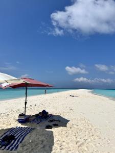 een strand met een parasol en een handdoek op het zand bij Madi Beach Guesthouse in Maalhos