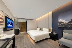 武漢市にあるAtour Hotel Wuhan Jianghan Road Jiangtanの白いベッドとテレビのある寝室