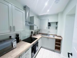 a kitchen with white cabinets and a sink at 1 Bed Apartment located in Huntingdon Town Centre - Designed for Contractors & Professionals - Free WiFi - Smart TV - Fully Equipped Kitchen - Ideal for Long Work Stays in Huntingdon +9 photos