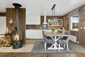 a kitchen with a table and chairs and a fireplace at Peaceful Cabin With View And Jacuzzi At Blefjell in Kongsberg