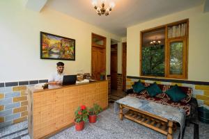 Een man aan een balie met een laptop. bij 360 Degree Kasol in Kasol