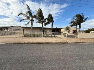 a house with palm trees in front of a fence at Shore Beats Work in Stansbury