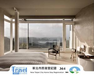 a bedroom with a bed and a chair and a large window at Daybreak in Jiufen