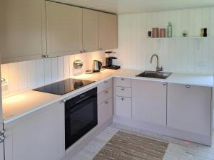 a white kitchen with white cabinets and a sink at Cottage Charm Near Lønstrup Lighthouse in Lønstrup