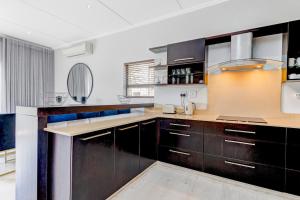 a kitchen with dark wood cabinets and white walls at Baluwatu 10, Zimbali Estate by Euphoric Leisure in Ballito +33 photos