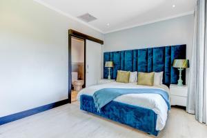 a bedroom with a large bed with a blue headboard at Baluwatu 10, Zimbali Estate by Euphoric Leisure in Ballito