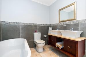a bathroom with a toilet and a sink and a mirror at Baluwatu 10, Zimbali Estate by Euphoric Leisure in Ballito