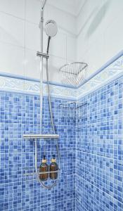 a blue tiled bathroom with a shower with three jars at Zorrilla - by Wehomes in Santander