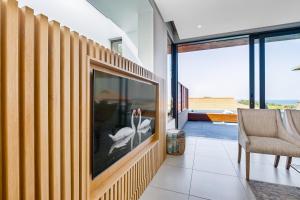 ein Wohnzimmer mit einem großen TV und einem Stuhl in der Unterkunft Oceans Edge 13, Zimbali Estate by Euphoric Leisure in Ballito
