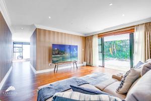 a living room with a couch and a tv at Phezulu Villas 2, Zimbali Estate by Euphoric Leisure in Ballito