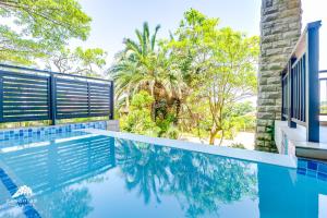 a swimming pool in front of a house with trees at Phezulu Villas 2, Zimbali Estate by Euphoric Leisure in Ballito