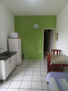 a kitchen with green walls and a table and a refrigerator at Hotel Paulista in Barra Velha