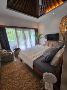 Un dormitorio con una cama grande y un televisor. en Villa Mustika, en Ubud